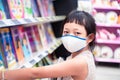 Asian little  child girl wear face mask and  buying school supplies in stationery store.Back to school concept Royalty Free Stock Photo