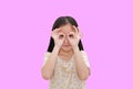 Asian little child looking through imaginary binocular on pink isolated background with clipping path