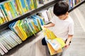 Asian little child sit on the floor,reading a cartoon from a fable book,happy kid boy enjoy in school library,excited kindergarten