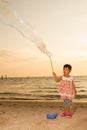Asian Little Chinese Girl Playing Soap Bubbles on the Beach Royalty Free Stock Photo