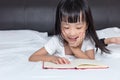 Asian little Chinese girl reading a book on bed Royalty Free Stock Photo