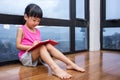 Asian little Chinese girl reading a book near the window