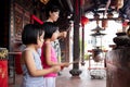 Asian Little Chinese Sisters and mother praying with burning incense sticks Royalty Free Stock Photo