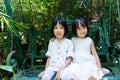 Asian Little Chinese Sisters sitting on bench