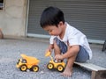 Asian little cute child boy playing yellow car truck toy outdoor