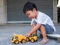 Asian little cute child boy playing yellow car truck toy outdoor