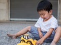 Asian little cute child boy playing yellow car truck toy outdoor