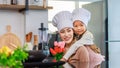 Asian little cute girl daughter smiling holding tulip flower bouquet hugging cuddling young cheerful female mother chef wearing Royalty Free Stock Photo