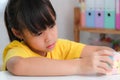 Asian little cute girl holding Rubik\'s cube in her hands and playing with it.