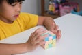 Asian little cute girl holding Rubik\'s cube in her hands and playing with it.