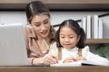 Asian little cute girl learning and studying her lesson with mother at home, schoolgirl pupil does homework with female tutor Royalty Free Stock Photo