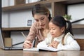 Asian little cute girl learning and studying her lesson with mother at home, schoolgirl pupil does homework with female tutor Royalty Free Stock Photo