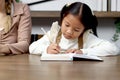 Asian little cute girl learning and studying her lesson with mother at home, schoolgirl pupil doing homework with tutor teacher, Royalty Free Stock Photo