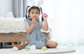 Asian little cute kid girl wearing bunny ears and enjoy painting on eggs for Easter holidays while sitting on floor at home Royalty Free Stock Photo