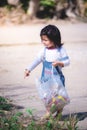 Asian little cute one girl is standing near garbage. She pointed her finger at debris on the floor.