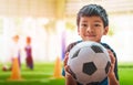 Little football boy with smile is holding a soccer ball with training ground backgorund Royalty Free Stock Photo