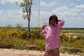 Asian little girl with bottle stands near the road