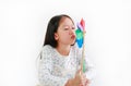 Asian little girl child blowing colorful pinwheel over white background. Kid hold and playing windmill in hand Royalty Free Stock Photo