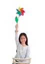 Asian little girl child showing colorful pinwheel isolated on white background. Kid hold windmill over head Royalty Free Stock Photo