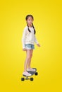 Asian little girl child skating on a skateboard isolated on yellow background. Kid riding on skateboard. Image with Clipping path Royalty Free Stock Photo