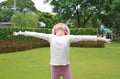 Asian little girl child wearing pink straw hat standing and open wide arms with looking to sky in the garden Royalty Free Stock Photo