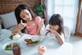 Asian little girl cover her mouth as her older sister feed her meals