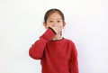 Asian little girl covering mouth with hand on white isolated background. Kid have a Secret concept