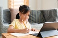 Asian little girl doing homework, learning, student using digital tablet. Homeschooling, Concept online learning at home Royalty Free Stock Photo