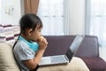 Asian little girl eating bread with using laptop Royalty Free Stock Photo