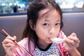 Asian little girl eating food with spoon and chopsticks in restaurant Royalty Free Stock Photo