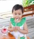 Asian little girl eating ice cream and holding spoon in mouth Royalty Free Stock Photo