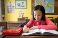 Asian little girl enjoy learning in classroom,portrait of a smiling child student studying holding pencil writing on book,sitting Royalty Free Stock Photo