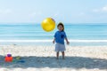 Asian little girl have fun and play yellow ball on the beach. Royalty Free Stock Photo