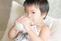 Asian little girl is holding and drinking a glass of milk in living room