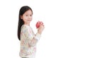 Asian little girl holding red apple in hands and looking it over white background. Side view Royalty Free Stock Photo