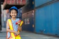 Asian little girl  holding walkie- talkie at Container cargo site. Business heir concept. Royalty Free Stock Photo