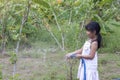 Asian little girl holds the blue rubber tube to inject to water the tree in the garden.