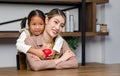 Asian little girl kid daughter holding red heart shape squeezing rubber ball smiling hugging cuddling embracing young female Royalty Free Stock Photo