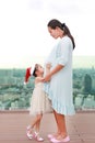 Asian Little girl kissing pregnant belly of her mother on the rooftop building Royalty Free Stock Photo