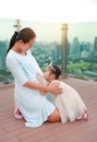 Asian Little girl kissing pregnant belly of her mother on the rooftop building at sunset Royalty Free Stock Photo