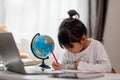 Asian little girl is learning the globe model, concept of save the world and learn through play activity for kid education at home Royalty Free Stock Photo