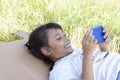 Asian little girl lying on the outdoor lawn and using of mobile phone have fun playing games in the garden.