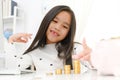 Asian little girl playing with coins making stacks of money,kid saving money for the future concept Royalty Free Stock Photo