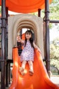 Asian little girl playing on the slider, Little pretty girl is while playing on the playground equipment in park Royalty Free Stock Photo