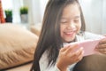 Asian little girl playing with smartphone, technology and communication concept - smiling girl texting on smartphone and lying in