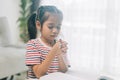 Asian little girl praying with rosary in hand at home Royalty Free Stock Photo