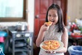 Asian little girl preparing and eating homemade pizza in the home kitchen with smile and happy Royalty Free Stock Photo