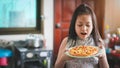 Asian little girl preparing homemade pizza in the home kitchen with surprise Royalty Free Stock Photo