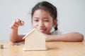 Asian little girl putting coin to house piggy bank shallow depth Royalty Free Stock Photo