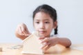 Asian little girl putting coin to house piggy bank shallow depth Royalty Free Stock Photo